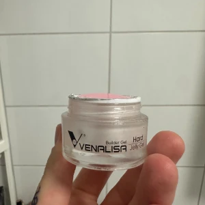 Venalisa Builder Gel rosa jelly - Venalisa Builder Gel Hard Jelly Gel i en snygg ljusrosa nyans. Kommer i en rund, genomskinlig burk med silvrigt skydd. Perfekt för att bygga och forma naglar med en geléliknande konsistens.