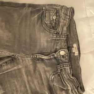 Grå raka jeans med fickdetaljer - Säljer ett par gråa bootcut jeans. Använda men inga skador eller fläckar på. Fickorna har knappdetaljer. Hoppas ni gillar!