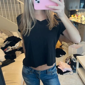 Svart t-shirt med lätt v-ringning - Säljer en svart t-shirt med v-ringad hals, så stilren och passar till allt! 🫶🏼 Tillverkad i mjuk bomull och perfekt för att klä upp eller klä ner. Oanvänd och passar S och M! Märket ”Blond Hour” sitter längst upp på baksidan, en riktigt snygg detalj 🌟