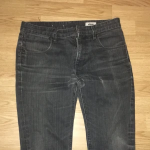 Svarta straight jeans från Réunion - Snygga svarta jeans från Réunion i klassisk straight modell. Jeansen har fem fickor, bälteshällor och subtila slitningar för en cool look. Materialet är jeans och passformen är normal, perfekt för dig som gillar stilrena och tidlösa byxor.