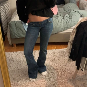 Blå bootcut jeans från Levis - Snygga blå med bootcut passform och låg midja. Klassisk femficksmodell med guldfärgade nitar och detaljerade sömmar. Jeansen är tillverkade i slitstarkt denim och har en cool vintagekänsla. Perfekta för dig som gillar retrostil. Jag säljer dem för att de tyvärr är för stora midjan på mig som ni ser på sista bilden har jag även försökt sy in dem. 