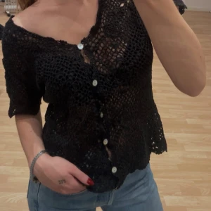 Svart virkad blus med knappar - Jätte snygg blus med v-ringning från Hennes Collection som inte kommer till användning. Går att ha både lite off shoulder och vanligt, eller med ett linne under. Står ingen storlek men skulle gissa på s. Passar xs-m🤎