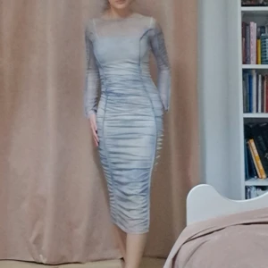 Grå meshklänning från Divided - Supersnygg grå långklänning från Divided i meshmaterial. Klänningen är tight, har långa ärmar och cool rynkad effekt längs hela kroppen. Den är figurnära och har en transparent känsla som ger en trendig vibe.