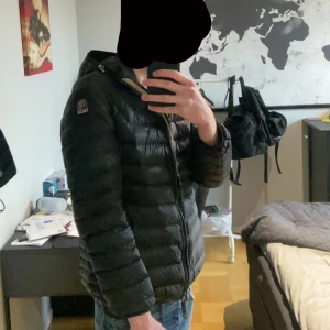 Parajumper jacka L - Säljer en svart dunjacka från Parajumpers i storlek L. Jackan är superlätt och har en quiltad design med dragkedja framtill. Klassisk look med huva och snygg patch på axeln. Perfekt för kalla dagar när du vill hålla stilen.