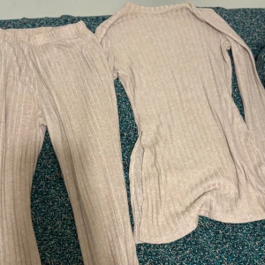 Beige ribbade byxor och tröja från SHEIN - Säljer ett par beige ribbade byxor och en tröja  från SHEIN i storlek S. Tröjan och Byxorna har en mjuk och stretchig känsla, raka ben och resår i midjan. Och tröjan har en slits på båda sidorna.Perfekta för en chill och avslappnad look. Materialet är viskos och elastan för extra komfort.
