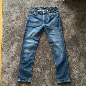 Jack & Jones jeans regular fit - Snygga blå Jack & Jones jeans med regular fit och klassisk femficksdesign. Jeansen har en mörkblå tvätt och är tillverkade i stretchig denim för extra komfort. Perfekta för dig som gillar en avslappnad och tidlös stil.