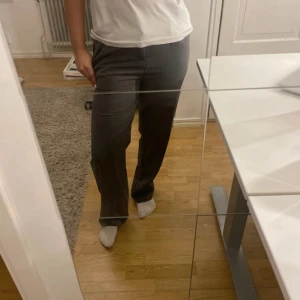 Grå kostymbyxor med raka ben - Snygga grå kostymbyxor med raka ben och klassisk passform. Byxorna har hällor för bälte, fickor i sidorna och stängs med knapp och dragkedja. Perfekta för en clean och stilren look. Materialet känns mjukt och har en lätt struktur.