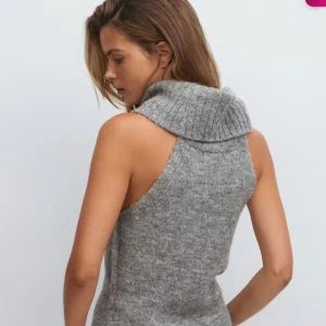 Grå stickad topp med polokrage - Säljer en grå stickad topp med bred, ribbad polokrage och ärmlös design. Helt ny med prislapp kvar. Vid intresse kan fler bilder skickas!