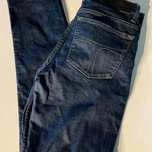 Tiger of Sweden jeans - Snygga mörkblå jeans från Tiger of Sweden med klassisk femficksdesign och kontrastsömmar. Jeansen har läderpatch på baksidan av midjan och den fräna T-designen på bakfickorna. Modellen heter Blaise och är slim fit. Jeansen var i storlek 31/34 men är uppsydda till 31/32. Kom gärna med frågor!