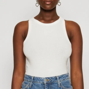 Vit ribbad linnetopp från Hollister - Säljer en fräsch vit ribbad linnetopp från Hollister i storlek S. Toppen har en rund halsringning och är ärmlös med en tight passform. Perfekt att styla med jeans eller shorts för en clean look. Materialet är mjuk bomull med stretch för extra komfort.