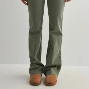 Gröna bootcut jeans med broderade fickor - Snygga gröna jeans med bootcut passform och broderade detaljer på bakfickorna. Byxorna har klassisk femficksdesign och är tillverkade i ett mjukt bomullsmaterial med lite stretch för extra komfort. Perfekt för dig som gillar en avslappnad men trendig look.  Storlek 36