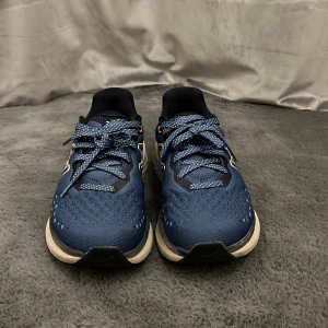 Karhu Mestari Run blå sneakers - Snygga Karhu Mestari Run sneakers i marinblått med vita och orange detaljer. Ovandelen är i mesh för bra andningsförmåga och skorna har en tjock, vit sula för extra komfort. Prickiga snören och coolt Karhu-märke på sidan. Perfekta för dig som gillar stilrena löparskor.