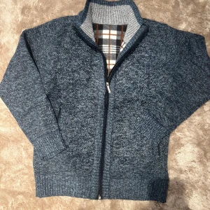 Onewear stickad overshirt - Mysig blåmelerad stickad kofta ifrån onewear med hel dragkedja och ståkrage. Insidan har ett rutigt foder i grått, brunt och vitt som ger extra värme. Perfekt för kyliga dagar och har ribbade muddar vid ärmslut och nederkant. Köp denna och glid runt på stan som grischast i stan! 🤩🇸🇪nypris 1099 mitt pris även fast den är helt ny 499 kr🔥💸. Fraktar mellan 1-2 dagar eller samma dag om köpet genomförs innan klockan 14!