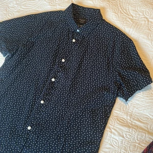 Blå kortärmad skjorta från Selected Homme - Snygg mörkblå skjorta från Selected Homme. Skjortan har korta ärmar, klassisk krage och vita knappar framtill. Regular fit.