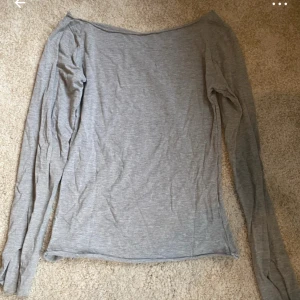 Ljusgrå långärmad offshoulder topp - Säljer en stilren ljusgrå långärmad topp med offshoulder-design. Tunn och mjuk i materialet, perfekt för att skapa en chill och enkel look. Passformen är normal och tyget är slätt utan mönster. Snygg att matcha med jeans eller kjol.
