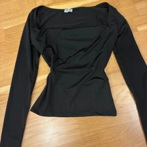 Svart långärmad topp från Bubbleroom - Säljer en svart långärmad topp från Bubbleroom med fyrkantig halsringning och figurnära passform. Toppen är tillverkad i mjuk polyester och har en stilren, enkel design som är lätt att matcha med olika outfits.