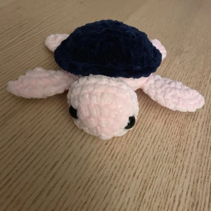 Virkad sköldpadda - Bilderna visar en söt, handgjord mjukdjurssköldpadda i rosa och mörkblå. Virkad av mig