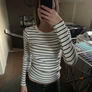 Randig långärmad tröja Gina Tricot - Säljer en vit och svart randig långärmad tröja från Gina Tricot, Basically Basics-kollektionen. Tröjan har rund halsringning och är figurnära i modellen.