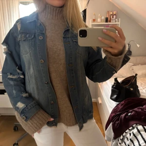 Jeansjacka från The Style Between Us - Säljer en blå jeansjacka med coola slitningar och tryck på ryggen. Jackan har knappar framtill. Köpt på Vinted men kommer inte till användning, aldrig använd själv!