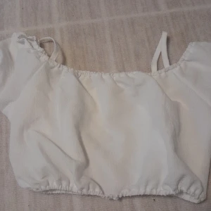 Vit croppad linnetopp från SHEIN - Säljer en vit croppad linnetopp från SHEIN med smala axelband och resår vid halsringning och nederkant. Toppen är ärmlös och har en lätt, skrynklig struktur i polyester. Perfekt för sommarens varma dagar och enkel att matcha med jeans eller kjol. Storleken motsvarar ungefär xs. Skriv för frågor osv!💕 (ENDAST SWISH)