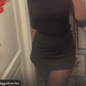 Svart minikjol med slits - Snygg svart minikjol med en liten slits framtill som ger en extra edge. Kjolen har en tight passform och är perfekt för dig som gillar stilrena och enkla plagg. Materialet känns mjukt och följsamt mot kroppen. Nytt pris 299kr