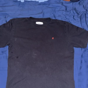 Mörkblå t-shirt från Replay - En stilren svart t-shirt från Replay med en liten röd broderad 'R' på bröstet. Klassisk passform med rund hals och korta ärmar. Perfekt basplagg till garderoben.