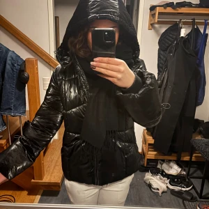 Glansig dunjacka  - Säljer en svart glansig pufferjacka från GUESS som är köpt som XS förra vintern, men skulle säga att den sitter som en S kanske till och med M. Knappt använd men är superfin med figursydd midja och armar vilket ger en fin form. 