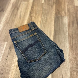 Mörkblå jeansbyxor från Nudie Jeans - Säljer ett par klassiska mörkblå jeans från Nudie Jeans med orangea sömmar och femficksdesign.                W26 L32                           Ett par mer jeans i profilen att välja mellan
