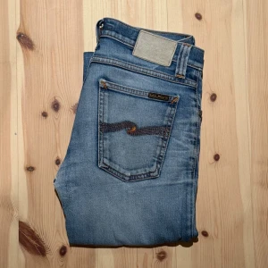 Nudie Jeans Tube Kelly - Tja! Säljer dessa riktigt snygga Tube Kellys, Jeansen är i relativt bra skick och är i storleken W28/L32. De har tydliga slitningar på låren och knäna samt en midre mellan benen. Skick enligt bilder. Hör av dig vid funderingar eller pris förslag!🙌