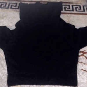 Svart polotröja med korta ärmar - Svart polotröja med hög krage och korta ärmar. Tröjan har en enkel och stilren design som passar perfekt till jeans eller kjol. Materialet känns mjukt och bekvämt mot huden, och den svarta färgen gör den lätt att matcha med olika outfits.