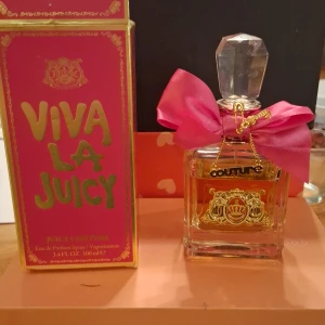Viva La Juicy EdP 100ml - Juicy Couture Viva La Juicy Eau de Parfum i en lyxig flaska med rosa rosett och gulddetaljer. Volym: 100 ml. Perfekt för dig som vill sticka ut med en ikonisk och trendig parfym.   Se bild hur mycket som är kvar .