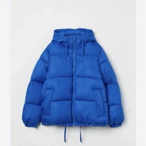 Blå pufferjacka med huva - Säljer en blå pufferjacka med huva och dragkedja framtill. Jackan har snörning i nederkant och två stora fickor på sidorna. Perfekt för kalla dagar och riktigt varm. Som ny, använd typ 2ggr💕skriv för fler bilder!