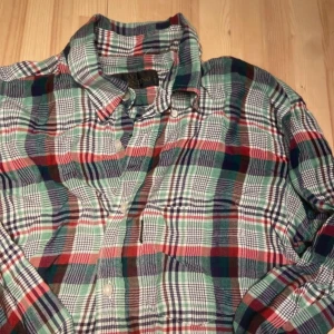 Rutig skjorta från Valentino  - Riktigt snygg rutig skjorta från Valentino Jeans i bomull. Skjortan har gröna, röda, blå och vita toner, klassisk krage och knäppning framtill. Perfekt för dig som gillar en avslappnad men ändå stilren look.