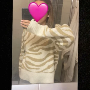 Beige zebramönstrad stickad tröja Gina Tricot - Säljer en beige och vit stickad tröja från Gina Tricot i storlek L, passar dock mig som har strl xs/s vanligtvis. Tröjan har zebramönster, ribbad hög hals och långa ärmar med breda muddar. Perfekt för dig som gillar djurmönster och vill ha en mysig, trendig look.