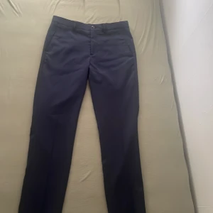 Svarta kostymbyxor från Jack & Jones - Säljer ett par eleganta mörkblå kostymbyxor från Jack & Jones i storlek 46. De har en super slim passform som ger en stilren och modern look. Byxorna är perfekta för formella tillfällen eller när du vill klä upp dig lite extra. 