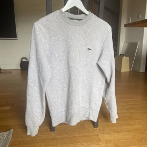 Grå Lacoste tjocktröja  - Super fin grå tjocktröja från Lacoste storlek S säljer för 850! Super skick och jätte fin! Inga fickor.