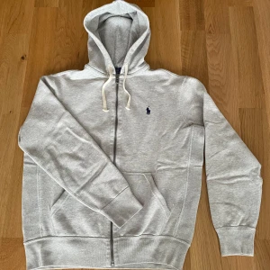 Polo Ralph Lauren zip hoodie - Storlek M i melerad grå. Hoodien är i väldigt fint skick utan noppor eller andra defekter. Hör av er om frågor!
