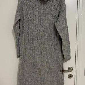 Grå stickad klänning - Säljer en mysig grå stickad klänning som är perfekt för kyligare dagar. Klänningen har en lång och bekväm passform med långa ärmar. Den är idealisk för både vardag och festliga tillfällen under höst och vinter.