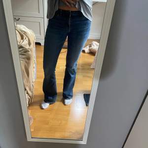 Säljer ett par snygga mörkblå bootcut jeans. De är lågmidjade och har en klassisk femficksdesign med dragkedja och knapp. Perfekta för både vardag och fest!