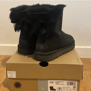 Äkta uggs  - Äkta uggs svarta med rosett baktill. Jättefina knappt defekter då de knappt är använda. 