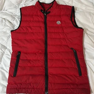 Moncler väst - Säljer just nu en moncler väst av färgen röd. Passar bra till hösten när de är lite sådär väder. Vill bara bli av med den då den inte passar mig längre. Kom med bud pris går att sänkas.