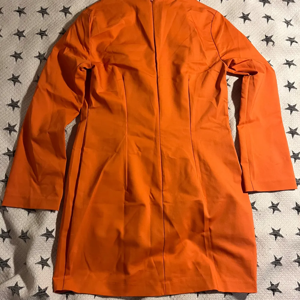 Säljer en snygg orange klänning i storlek 46/XL. Den har en enkel och stilren design med långa ärmar och en dragkedja i ryggen. Perfekt för höst- och vårsäsongen! Helt oanvänd med lappen kvar.. Klänningar.