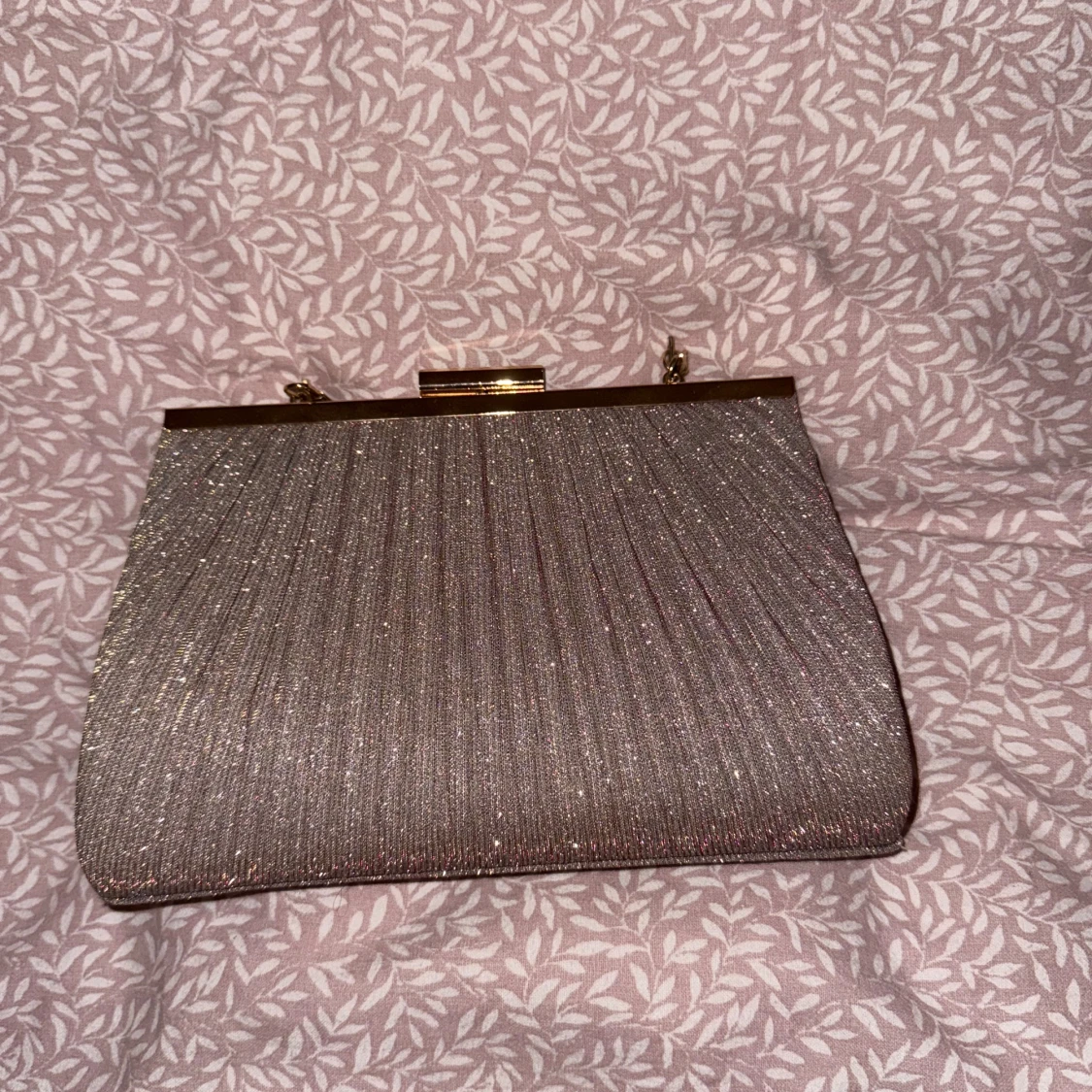 Glittrig kuvertväska med gulddetaljer