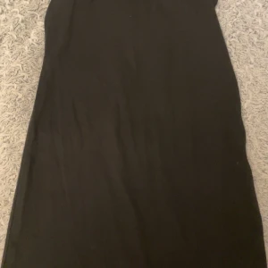 Svart klänning - En stilren svart klänning med enkel design. Perfekt för olika tillfällen med sin tidlösa look.