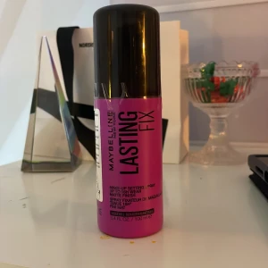 Maybelline Lasting Fix Makeup Setting Spray - Maybelline Lasting Fix Makeup Setting Spray i en livlig rosa flaska med svart lock. Denna spray hjälper till att hålla sminket på plats hela dagen med en matt finish. Perfekt för att förlänga hållbarheten av din makeup. Aldrig använd. Helt ny. 
