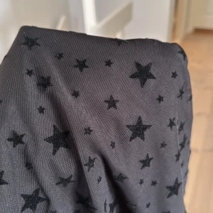 Svart meshtröja med stjärnor  - Snygg svart meshtröja  med ett coolt stjärnmönster. Tröjan är långärmad och perfekt för lager-på-lager-stil. Den genomskinliga designen ger en trendig look.