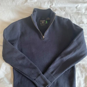 Mörkblå tröja med dragkedja från Dockers - Säljer en stilren mörkblå tröja från Dockers med halv dragkedja. Tröjan har långa ärmar och är perfekt för kyligare dagar.