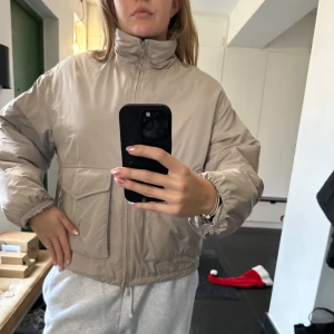 Beige pufferjacka från &OtherStories - Säljer en beige pufferjacka med dragkedja och hög krage från &OtherStories. Använt bara några gånger. Passar S och M.