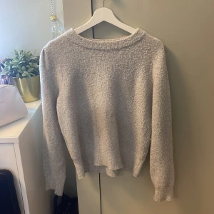 Grå stickad tröja - Mysig grå stickad tröja med rund hals och långa ärmar. Perfekt för kyliga dagar och enkel att matcha med olika outfits. Storlek M men passar även för folk som i vanliga fall har S. Den har tvättats i fel grad en gång och är därför lite nopprig, men det är inget man märker av. 
