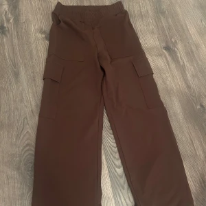 Bruna cargopants - Snygga bruna cargopants med praktiska fickor på sidorna. Perfekta för en avslappnad stil och bekväma att bära hela dagen. Elastisk midja för extra komfort.
